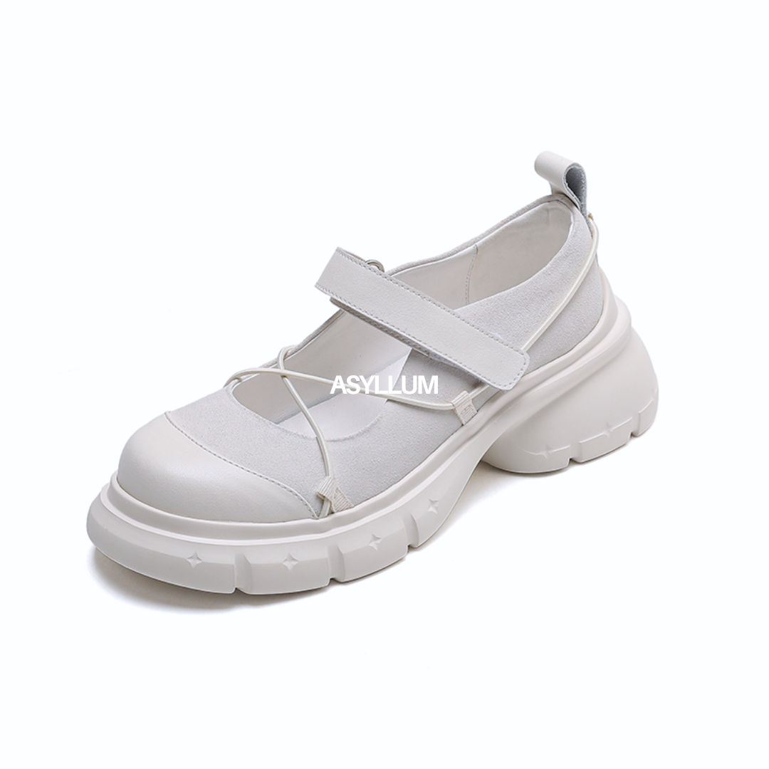White Mary Jane shoe with a thick sole on a white background, featuring the brand 'ASYLLUM'.
