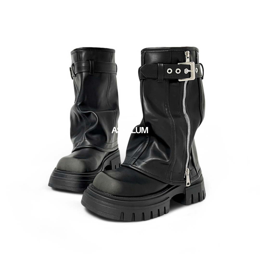 A pair of black vegan leather mid-calf boots with chunky platforms, fold-over shafts, buckles, and side zippers.